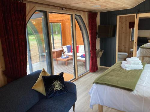 a room with a bed and a couch and a patio at Bedrule Old Manse Glamping in Hawick