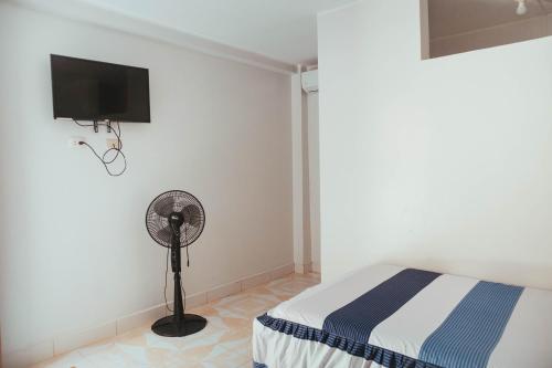 1 dormitorio con 1 cama, ventilador y TV en Hospedaje Garcilazo, en Yurimaguas