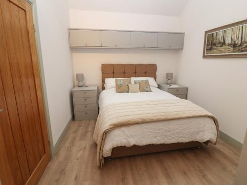 a bedroom with a large bed and two night stands at The Cow Shed at Pear Tree Farm in Doncaster