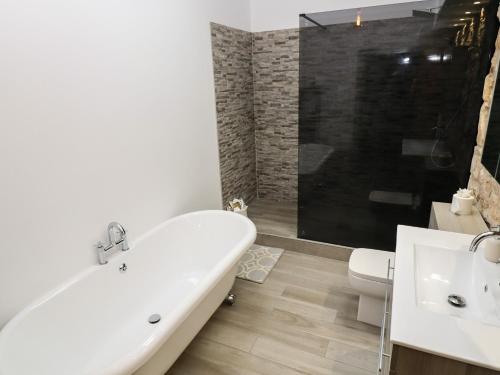 a bathroom with a tub and a toilet and a sink at The Cow Shed at Pear Tree Farm in Doncaster