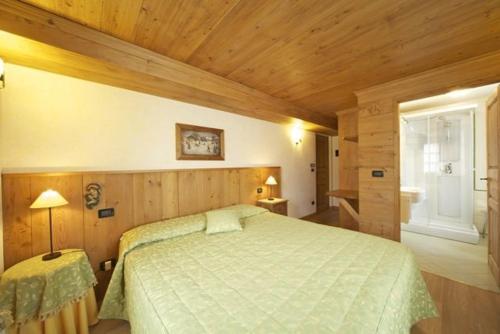 - une chambre avec un grand lit et un plafond en bois dans l'établissement Hotel Dente Del Gigante, à Courmayeur