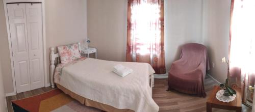 - une petite chambre avec un lit et une chaise dans l'établissement Private Home in downtown Edmundston!, à Edmundston