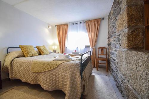 a bedroom with a bed and a stone wall at Casinha da Deolinda in Aldeia das Dez