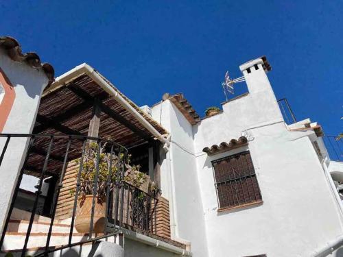a white building with a balcony and a blue sky at La casa del piano - Beautiful 18th century house with courtyard & pool in Jimena de la Frontera