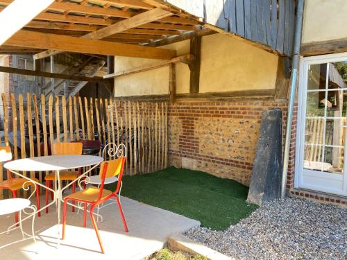 a patio with a table and chairs and a brick wall at La petite ferme de Roumare in Roumare