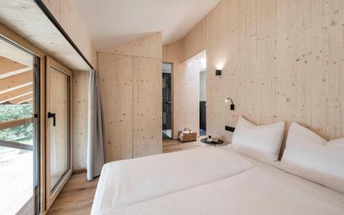 a bedroom with a white bed and a large window at Stadl Chalet oberhalb Brixen in Rosa