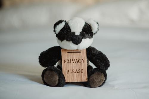 a black and white teddy bear holding a wooden sign at The Bonnie Badger in Gullane