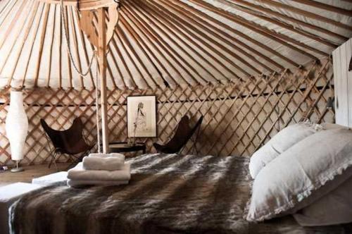 - une chambre dans une yourte avec un lit et des chaises dans l'établissement Le Relais de Roquefereau, à Penne-dʼAgenais