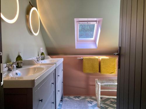 een badkamer met 2 wastafels en een raam bij Encore une fois, La grande maison in Locmalo