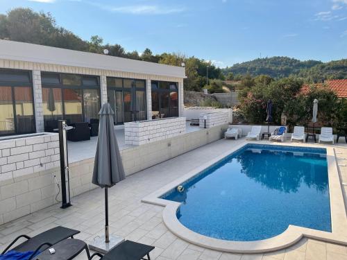 a pool with chairs and an umbrella next to a building at Villa 4 Princesses in Vela Luka