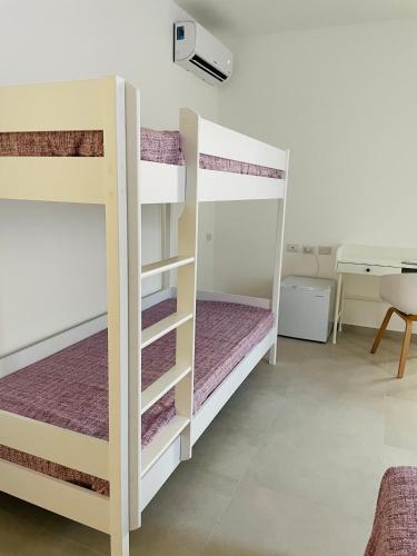 two bunk beds in a room with a desk at B&B S'arciaredda in SantʼAntìoco
