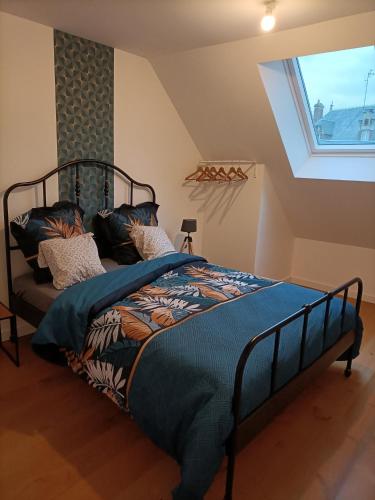 a bedroom with a bed with a blue comforter and a window at Petit Coin de Beauce in Toury