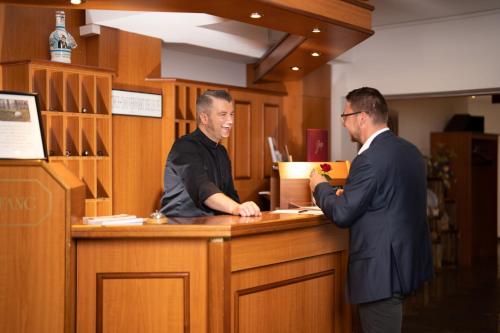 two men are standing at a counter in a law office at Hotel Reussischer Hof in Schmölln