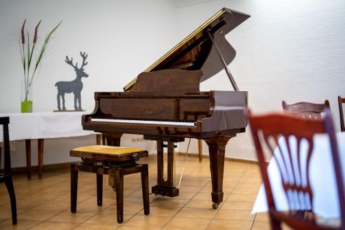 a piano with a stool next to a table at Hotel Reussischer Hof in Schmölln