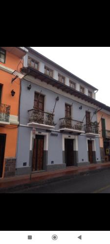un edificio blanco con ventanas y balcones en una calle en Hostal PASCO, en Quito