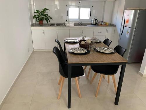 een keuken met een houten tafel en zwarte stoelen bij Alba II - Departamento 2 ambientes in Posadas
