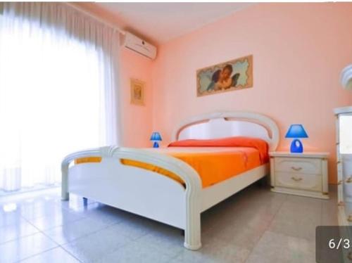 a bedroom with an orange and white bed and a window at Casa Vacanze Amici dell' Etna in Giardini Naxos