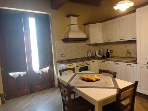 una cocina con mesa y sillas y una cocina con armarios blancos. en Ai doganieri, en Randazzo