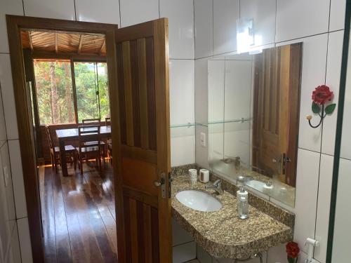 a bathroom with a sink and a mirror and a table at Casa Araucária in Visconde De Maua