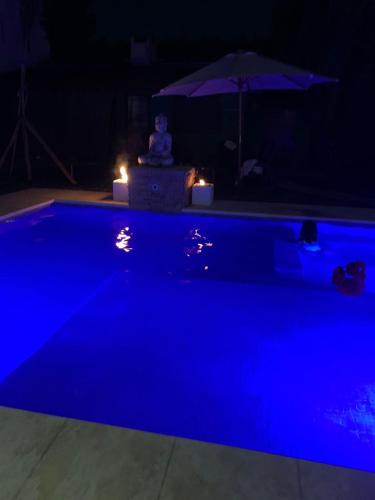 a blue swimming pool at night with an umbrella at Like at Home Ezeiza in Ezeiza