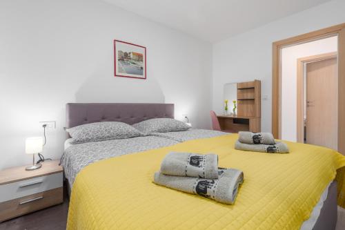 een slaapkamer met een geel bed en handdoeken bij Alex Deluxe Apartments on Beach in Poreč