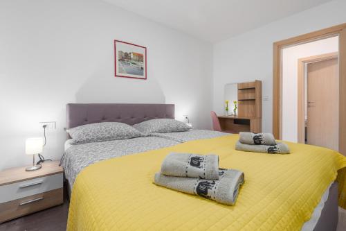 - une chambre avec un lit jaune et des serviettes dans l'établissement Alex Deluxe Apartments on Beach, à Poreč