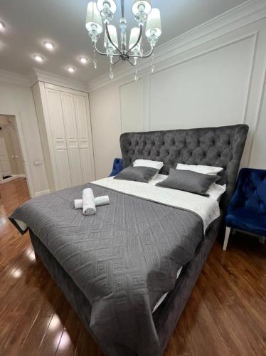 a bedroom with a large bed and a chandelier at Apartments in the Babylon residential complex in Almaty