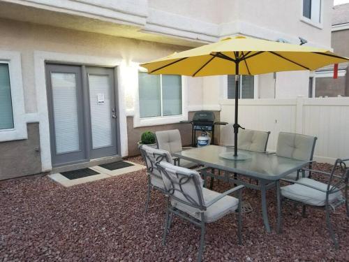 a table and chairs with a yellow umbrella on a patio at A - Fully remodeled and professionally decorated in Las Vegas