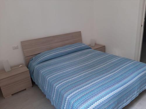 a bed with a blue striped blanket in a bedroom at Home Sweet Home in Civitavecchia