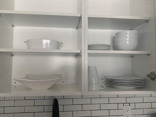 a kitchen cabinet filled with white dishes and plates at Sleeps 3, Cozy, Boho Style, in the heart of Miami -free parking in Miami