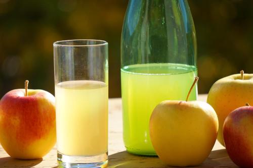 two glasses of orange juice and apples on a table at Waalhof Ferienwohnung Apfelblüte in Silandro