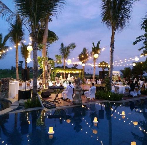 a resort pool with tables and palm trees at night at Kori Maharani Villas - Lagoon Pool Access 1 in Siyut