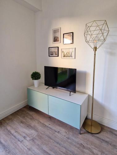 a living room with a television on a blue cabinet at HYPER CENTRE Gare RER A 250m Paris 20min in Poissy
