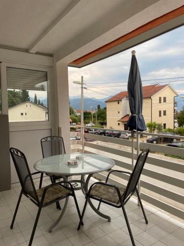 a glass table and chairs on a balcony with a window at Apartman Lucy in Baošići