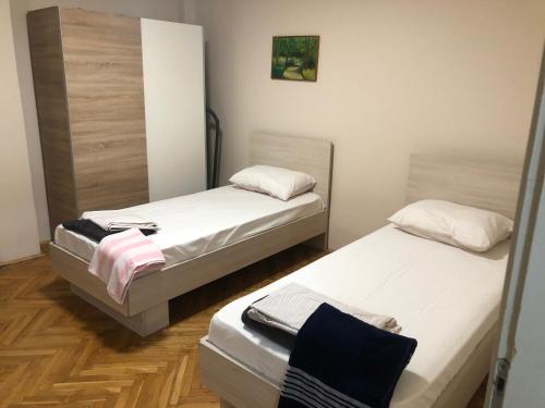 two beds in a room with wooden floors at Aleksandra in Skopje