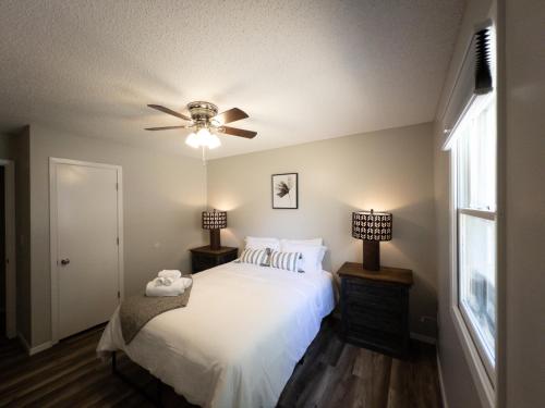 um quarto com uma cama branca e uma ventoinha de tecto em Subtle comfort and style in quiet neighborhood. em Joplin