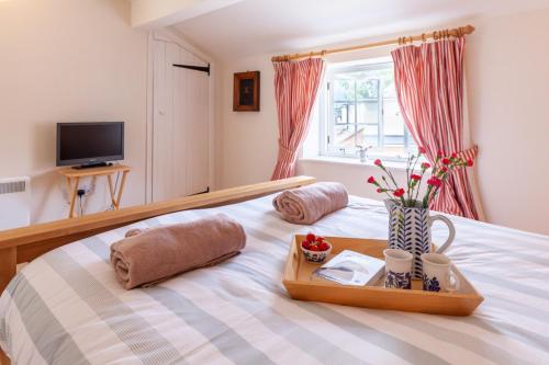 a bedroom with a bed with a tray with flowers on it at No. 4 Back Lane - Norfolk Cottage Agency in Burnham Market