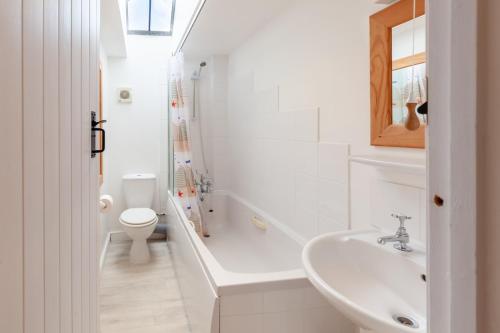 a white bathroom with a sink and a toilet at No. 4 Back Lane - Norfolk Cottage Agency in Burnham Market