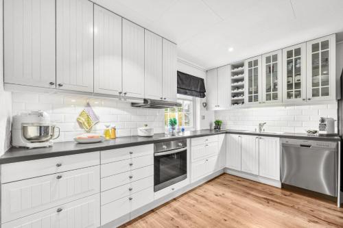 a white kitchen with wooden floors and white cabinets at private room in shared apartment in Trondheim