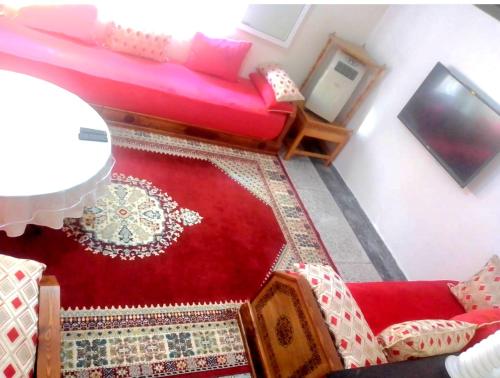 a living room with a red couch and a red rug at elkbira in Salé