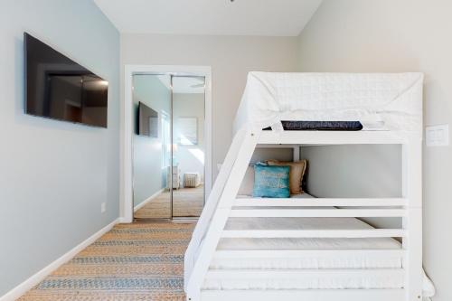 Una litera blanca en una habitación con escalera. en Dolphin Paradise Unit B, en South Padre Island