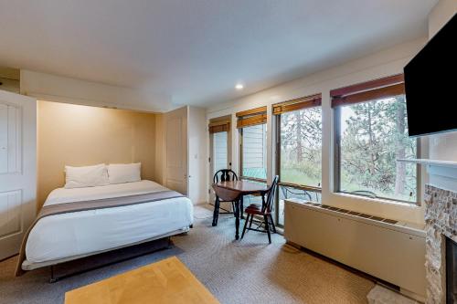 1 dormitorio con cama, mesa y ventana en Alpine Escape, en Bend