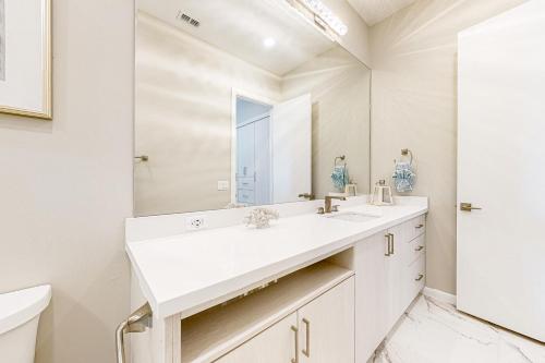 een witte badkamer met een wastafel en een spiegel bij Dolphin Paradise Unit A in South Padre Island