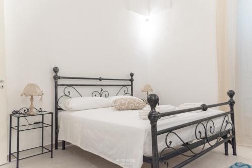 1 dormitorio con cama negra con sábanas y almohadas blancas en Il vecchio arco en Novoli