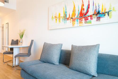 a blue couch in a living room with a painting on the wall at Vienna Residence, Marina Tower - Danube in Vienna