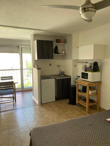 Il comprend une cuisine et un salon avec une table et un four micro-ondes. dans l'établissement STUDIO-CABINE CARNON-PLAGE, à Mauguio