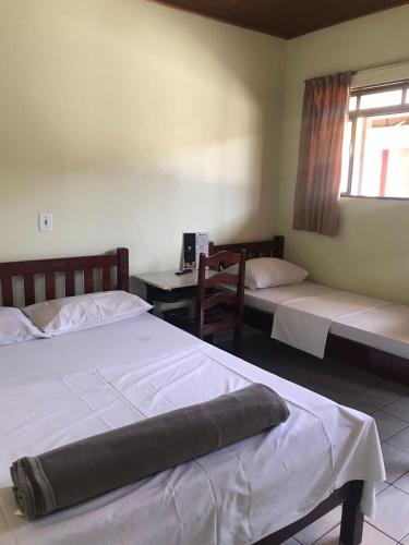 a bedroom with two beds and a table and a window at Hotel Park in Valparaíso de Goiás