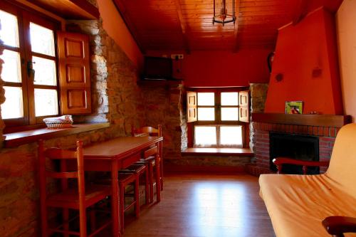 a room with a table and chairs and a fireplace at Apartamentos Rurales Las Cuendias in Perlunes