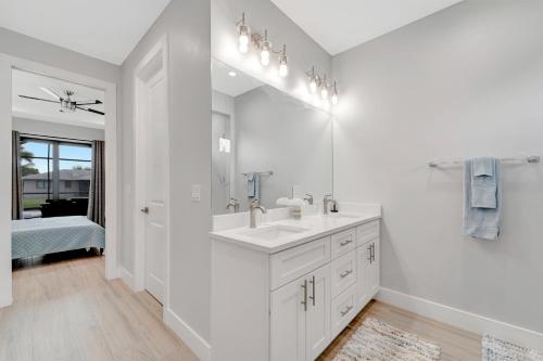 a white bathroom with a sink and a mirror at Seashell of the Ball in Cape Coral