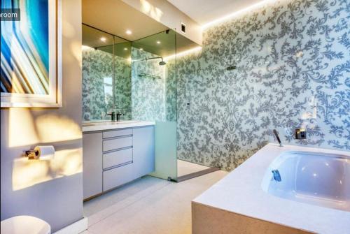 a bathroom with a tub and a sink and a mirror at Private Pool! Bantry Bay Large Flat with Solar in Cape Town